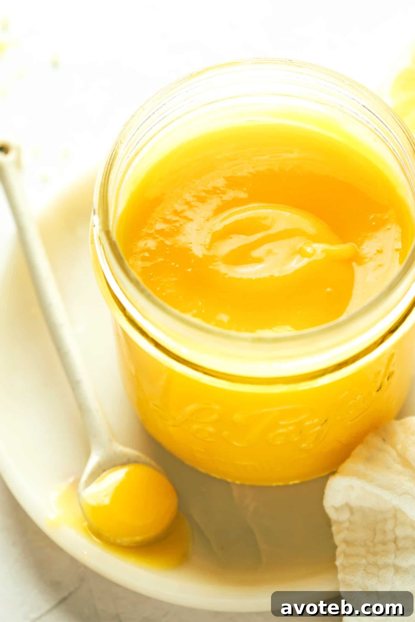 Jar of vibrant homemade lemon curd with a spoon