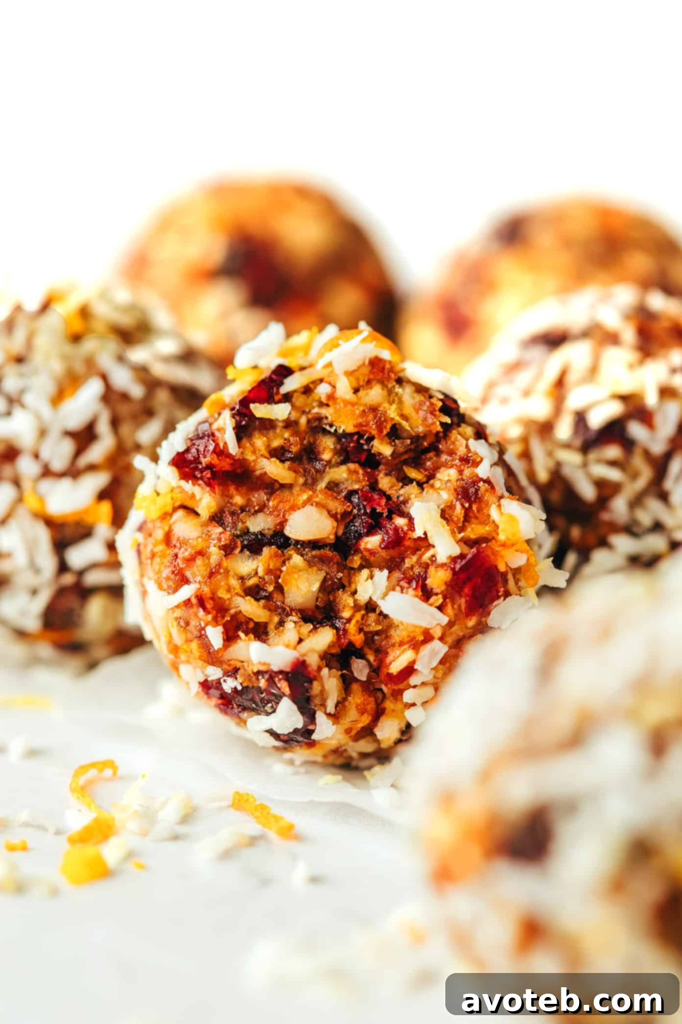 A vibrant close-up of a single cranberry orange almond energy bite, showing its detailed texture and the hint of orange zest and dried cranberries.