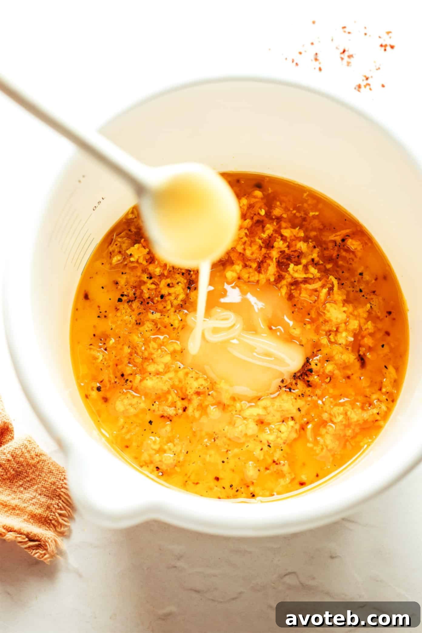 Close-up of the homemade Ginger Hot Honey Vinaigrette in a small bowl, showcasing its smooth texture and vibrant color.