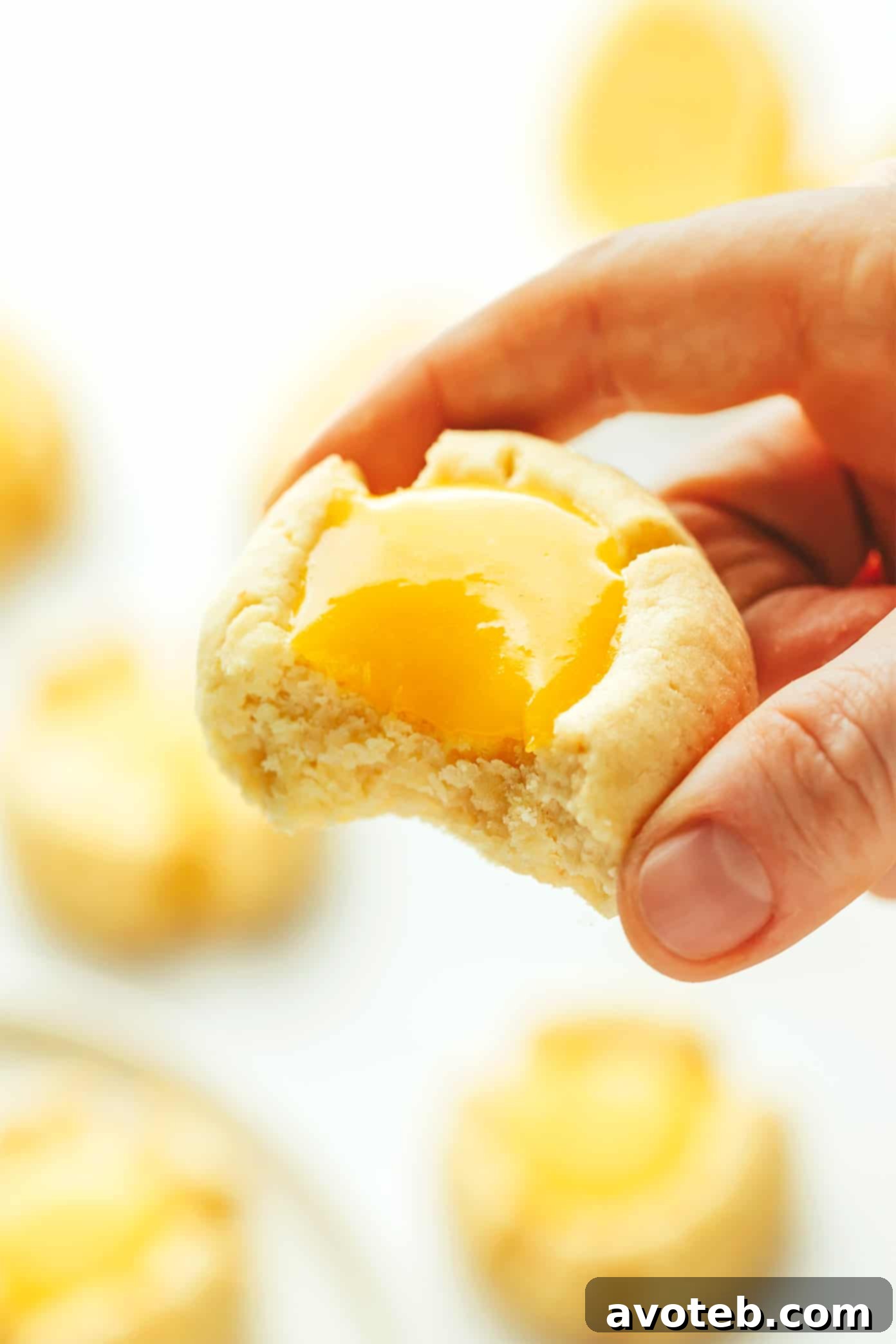 A lemon thumbprint cookie with a bite taken out, revealing its soft interior and lemon curd