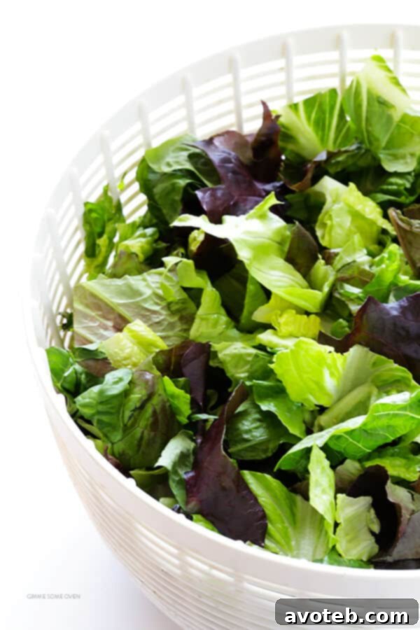 A bowl filled with crisp Romaine and red-leaf lettuce, thinly sliced red onion, and vibrant roasted red peppers, forming the foundation of the family's favorite salad.