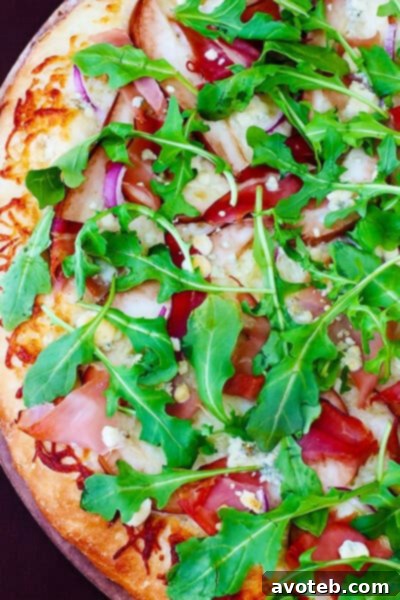 Close-up of baked Pear, Prosciutto, Arugula, and Gorgonzola Pizza showing melted cheese and toppings
