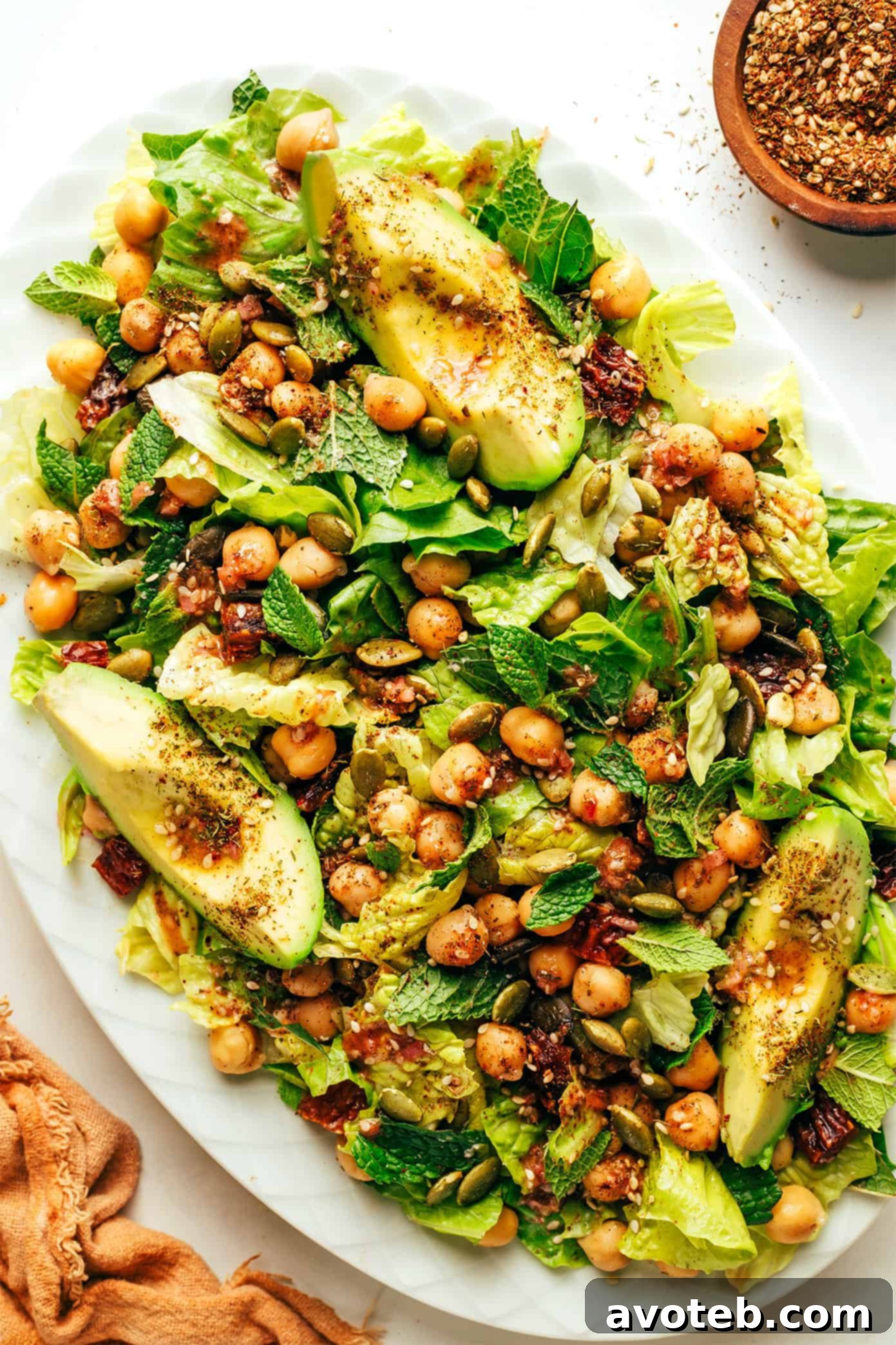 This vibrant green salad is loaded up with chickpeas, Medjool dates, avocado, pepitas, loads of fresh mint, and tossed with a lemony za'atar shallot vinaigrette. It's naturally vegan and gluten-free, but feel free to add a protein such as chicken, steak, shrimp or salmon if you'd like. So fresh and delicious! | gimmesomeoven.com Generous serving of Chickpea, Date, and Avocado Salad with Za'atar Vinaigrette on a serving platter