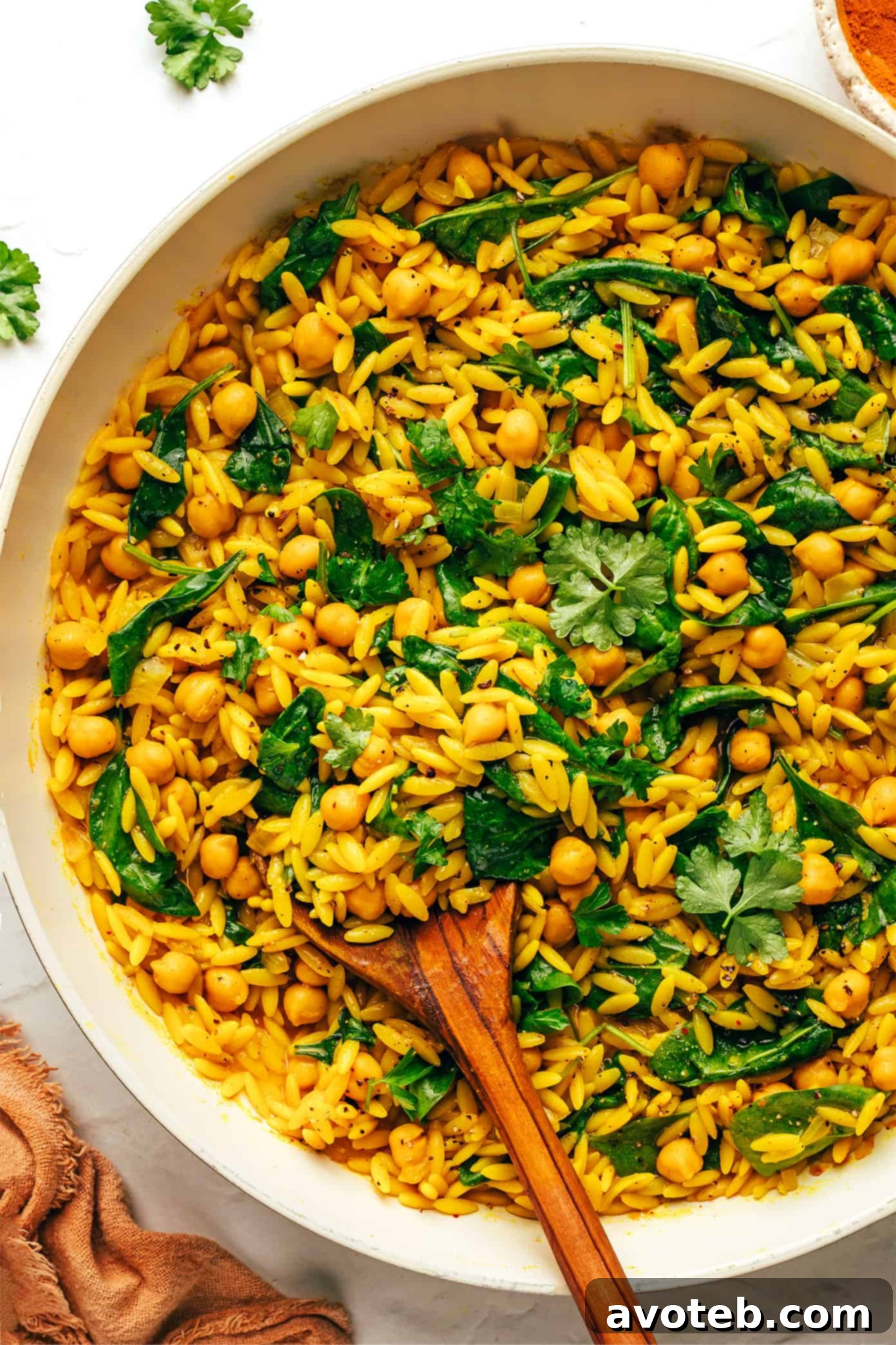 A serving of Lemony Spiced Orzo and Chickpeas in a bowl with a fork, ready to eat.