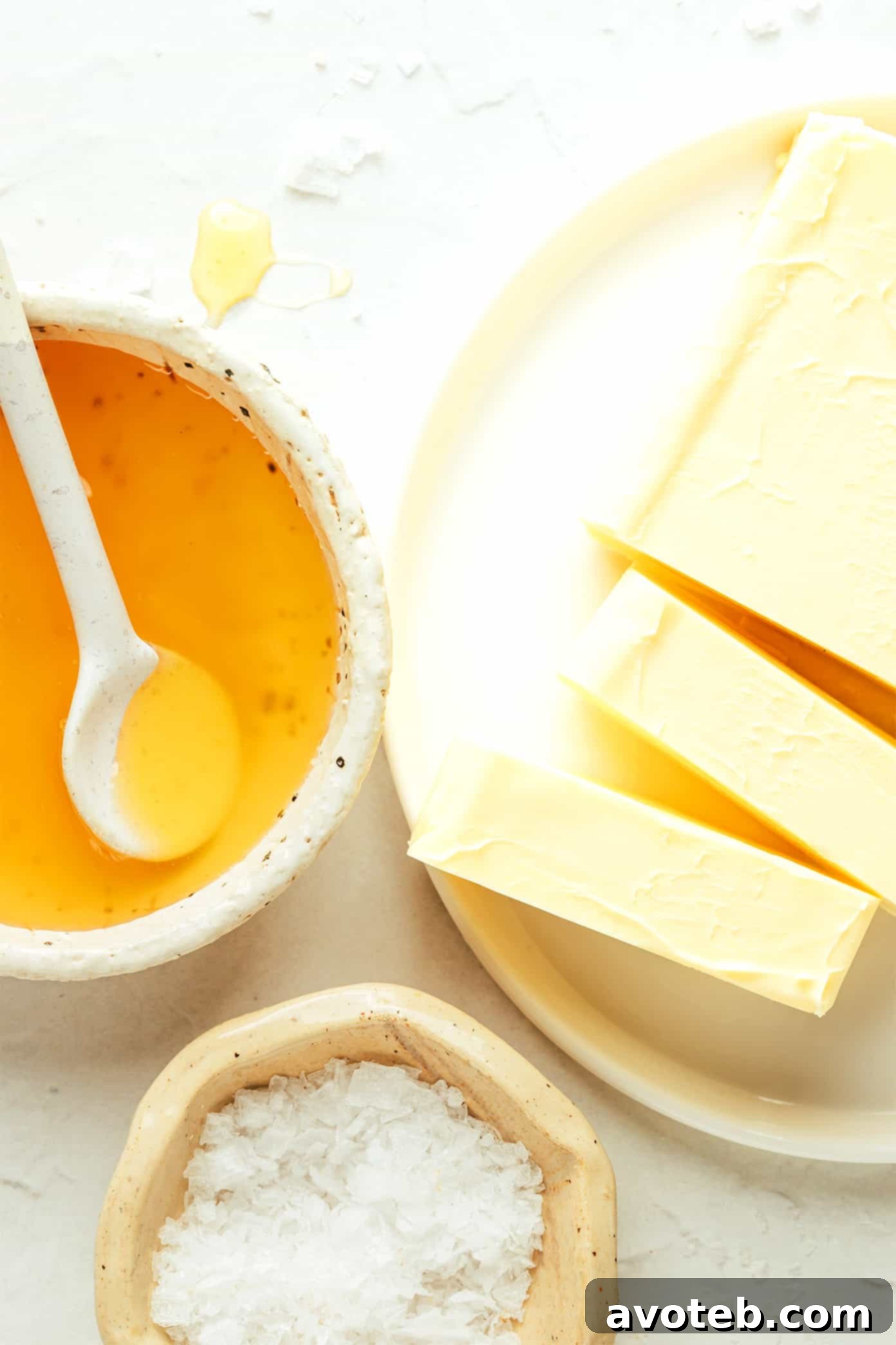 Ingredients for honey butter laid out: a stick of butter, a jar of honey, and a small dish of sea salt.