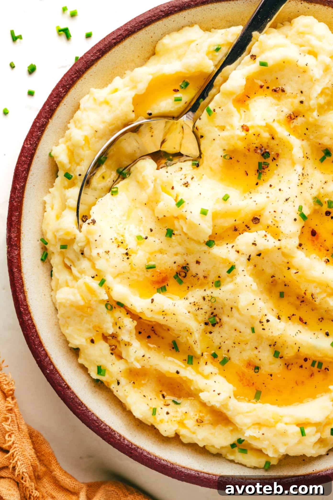 Golden Nutty Potato Mash 2 A close-up shot of creamy brown butter mashed potatoes, garnished with fresh chives, in a white serving bowl.