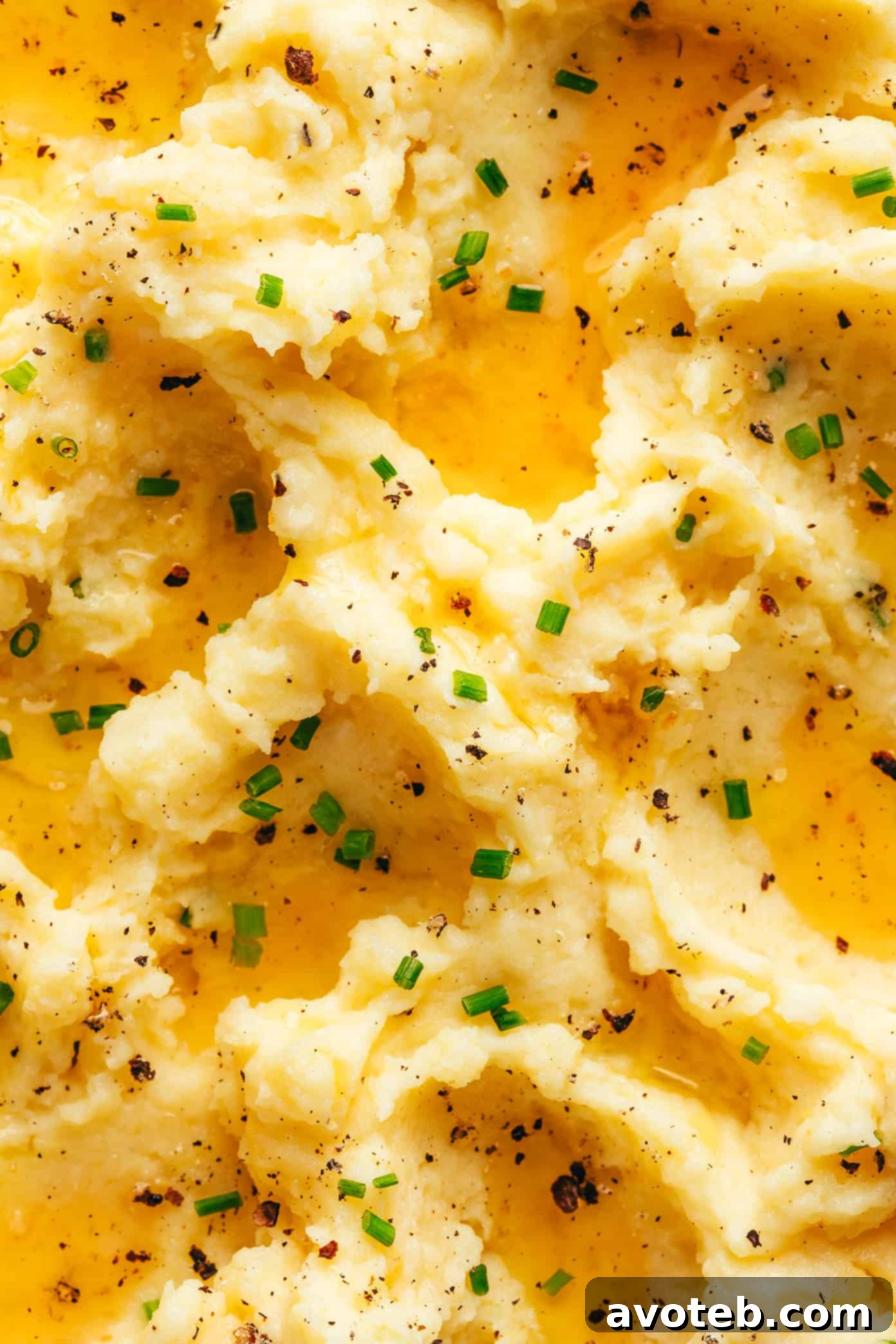 Golden Nutty Potato Mash 6 A top-down view of brown butter mashed potatoes in a white bowl, garnished with a generous amount of fresh chives.