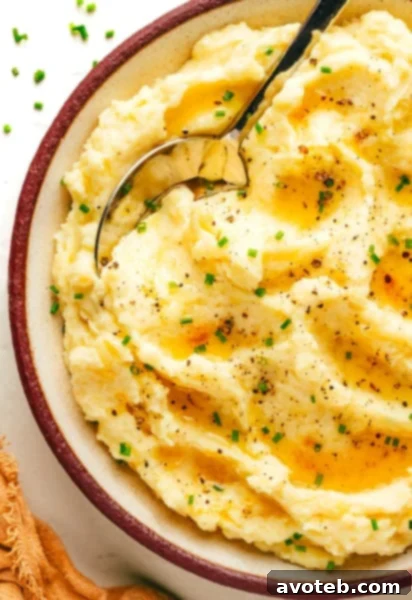 Brown Butter Mashed Potatoes, garnished with fresh chives, in a white serving bowl.