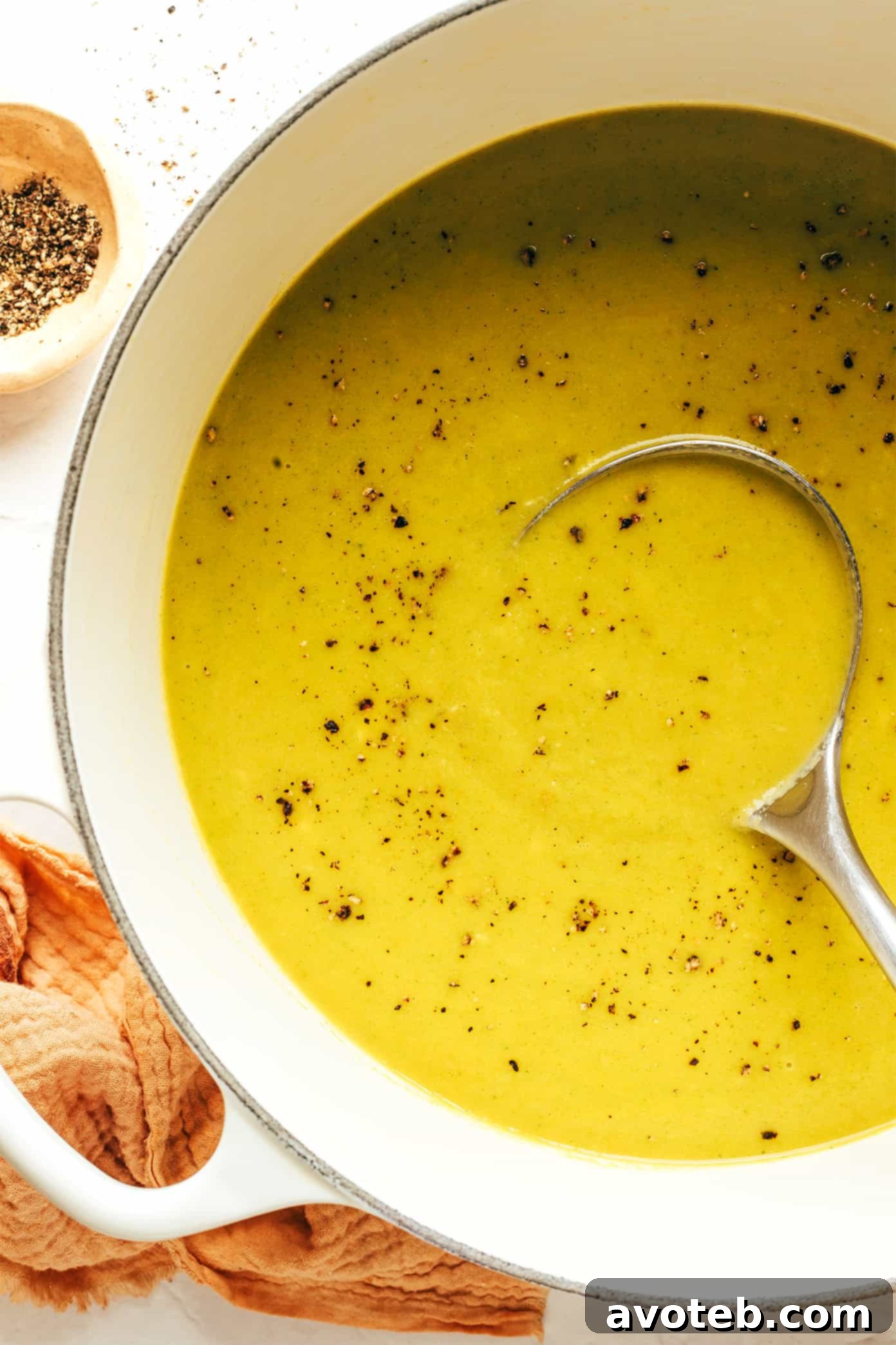 A beautifully set table with a bowl of lightened-up broccoli cheese soup, accompanied by fresh bread.