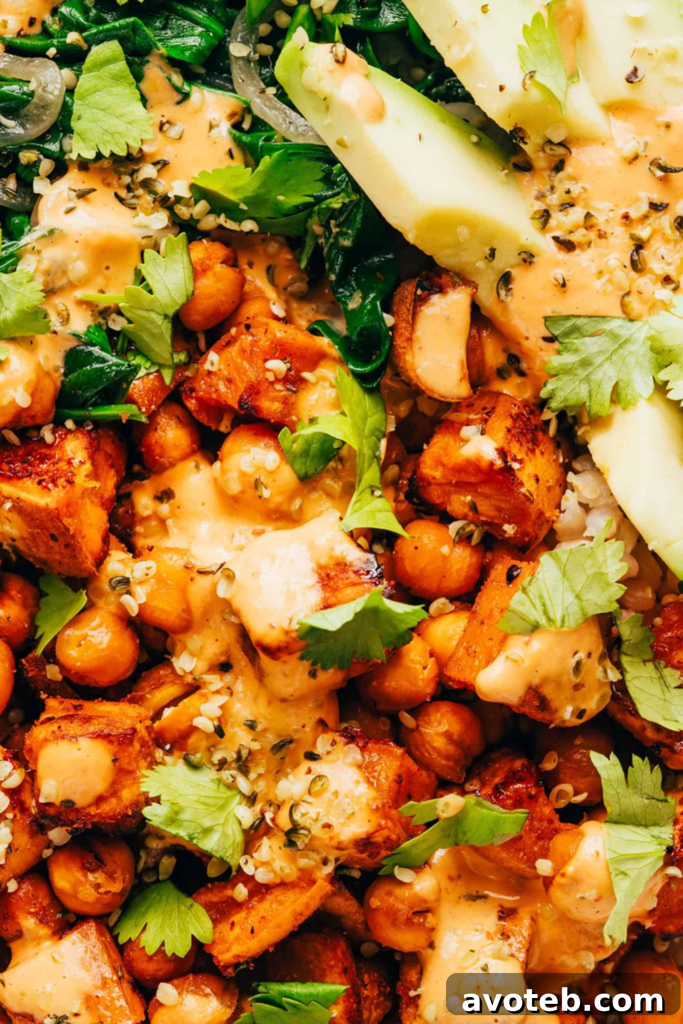 A large pan of roasted sweet potatoes and chickpeas, glistening with seasoning.