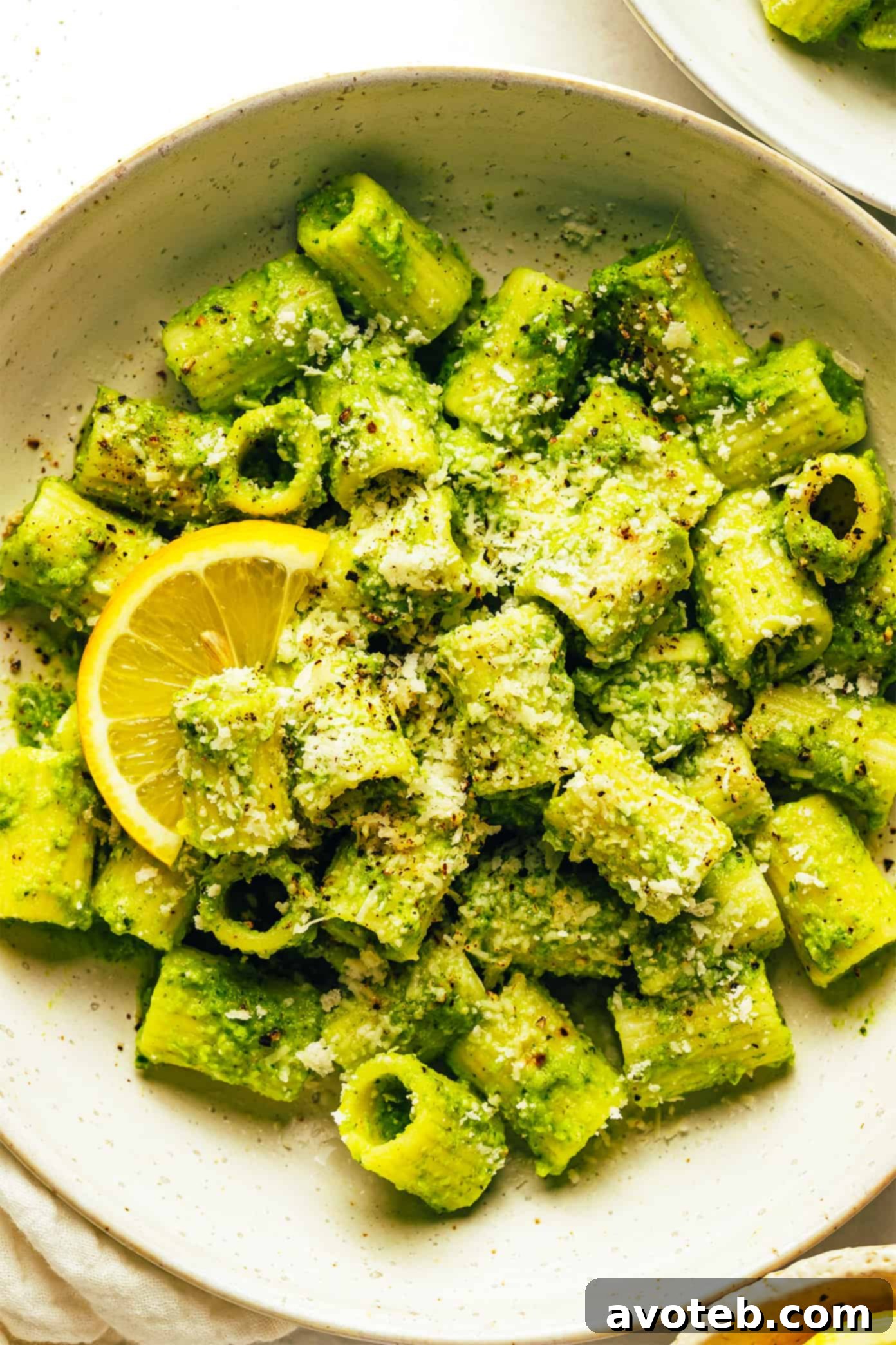 Overhead shot of Lemony Broccoli Pesto Pasta in a large serving bowl, with fresh lemons and herbs around.