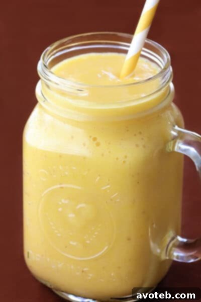 Vibrant yellow Pineapple Ginger Smoothie, close-up in a glass with a straw, capturing its refreshing texture.