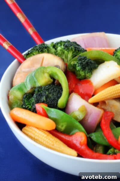 Close-up of a tall bowl of Ginger Vegetable Stir Fry, showcasing the fresh ingredients