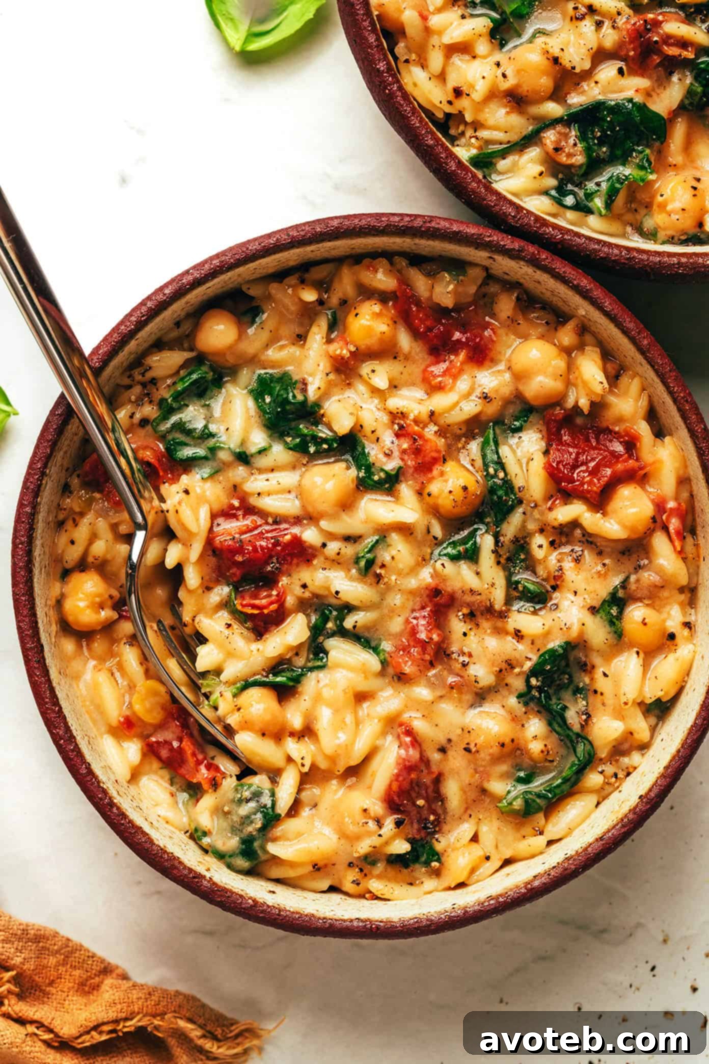 The final Marry Me Chickpeas and Orzo dish, still in the pan, garnished and ready to be served, showing steam and warmth.