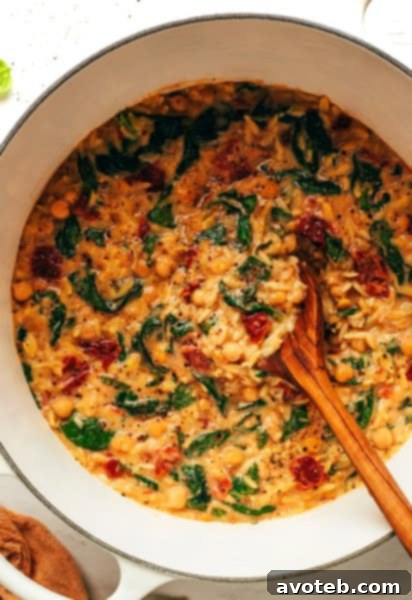 A bowl of Marry Me Chickpeas and Orzo, garnished with fresh herbs and Parmesan, ready to be enjoyed.