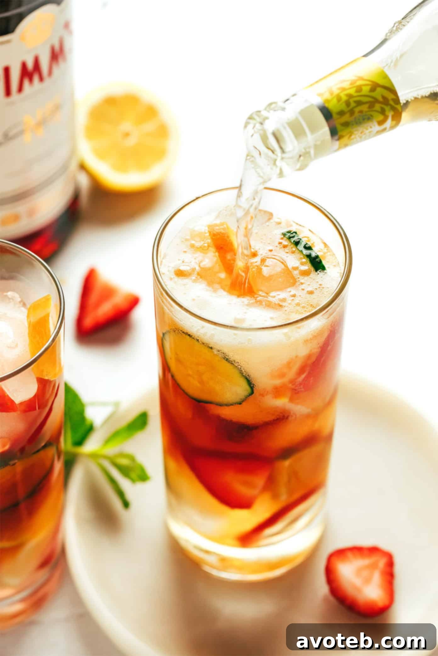 Ingredients for Pimm's Cup laid out on a table, including Pimm's No. 1 bottle, ginger ale, lemon, and fresh fruit