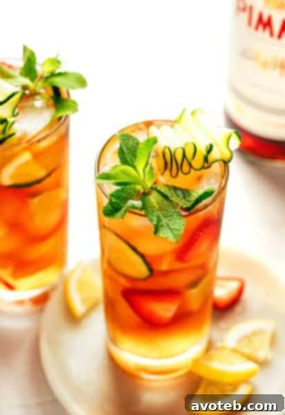 A refreshing Pimm's Cup cocktail garnished with fresh fruit, cucumber, and mint