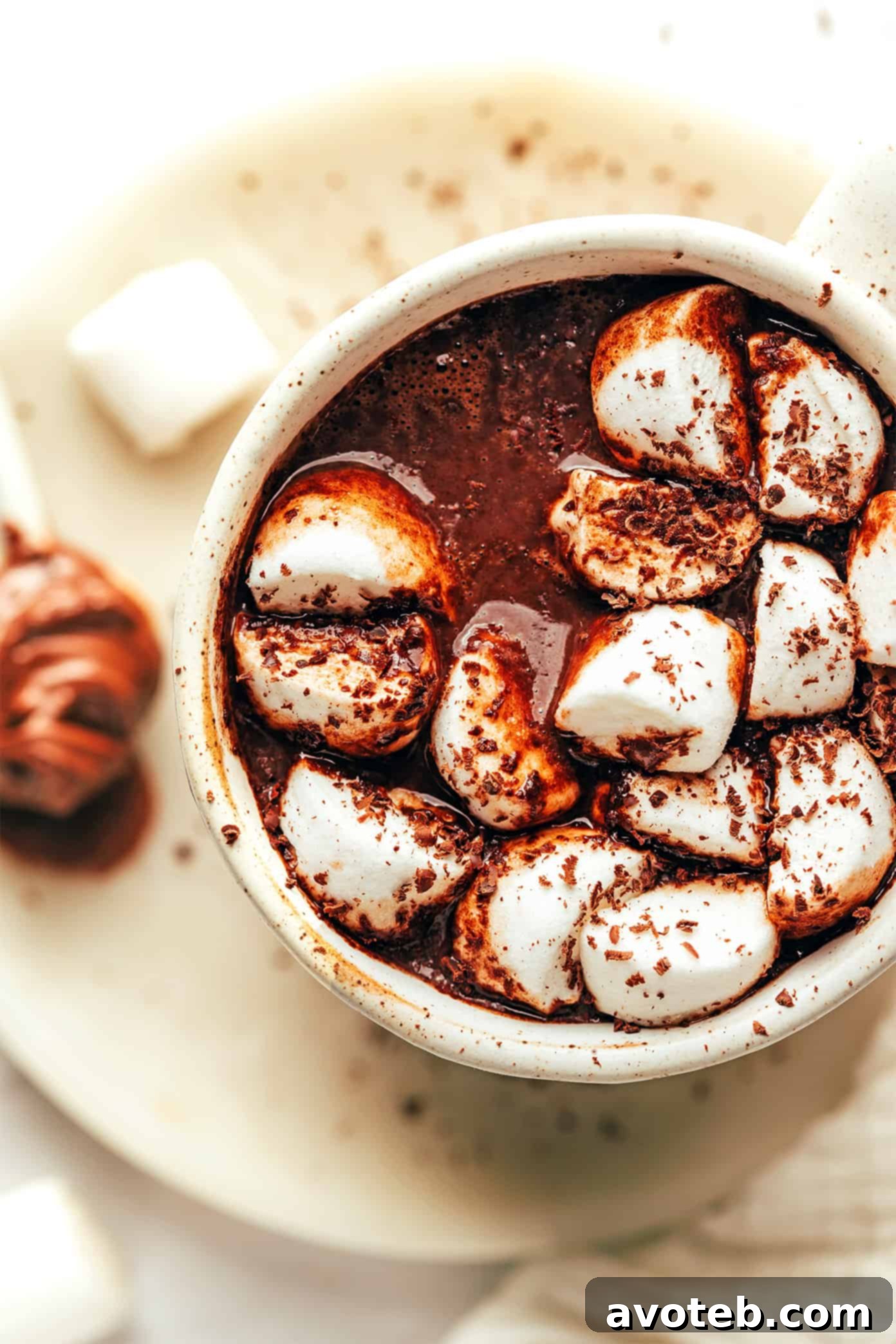 A steaming mug of Nutella hot chocolate, garnished with whipped cream and chocolate shavings.