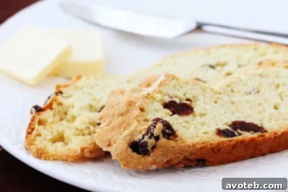 A warm slice of Irish Soda Bread with raisins, resting on a cutting board, ready to be enjoyed.