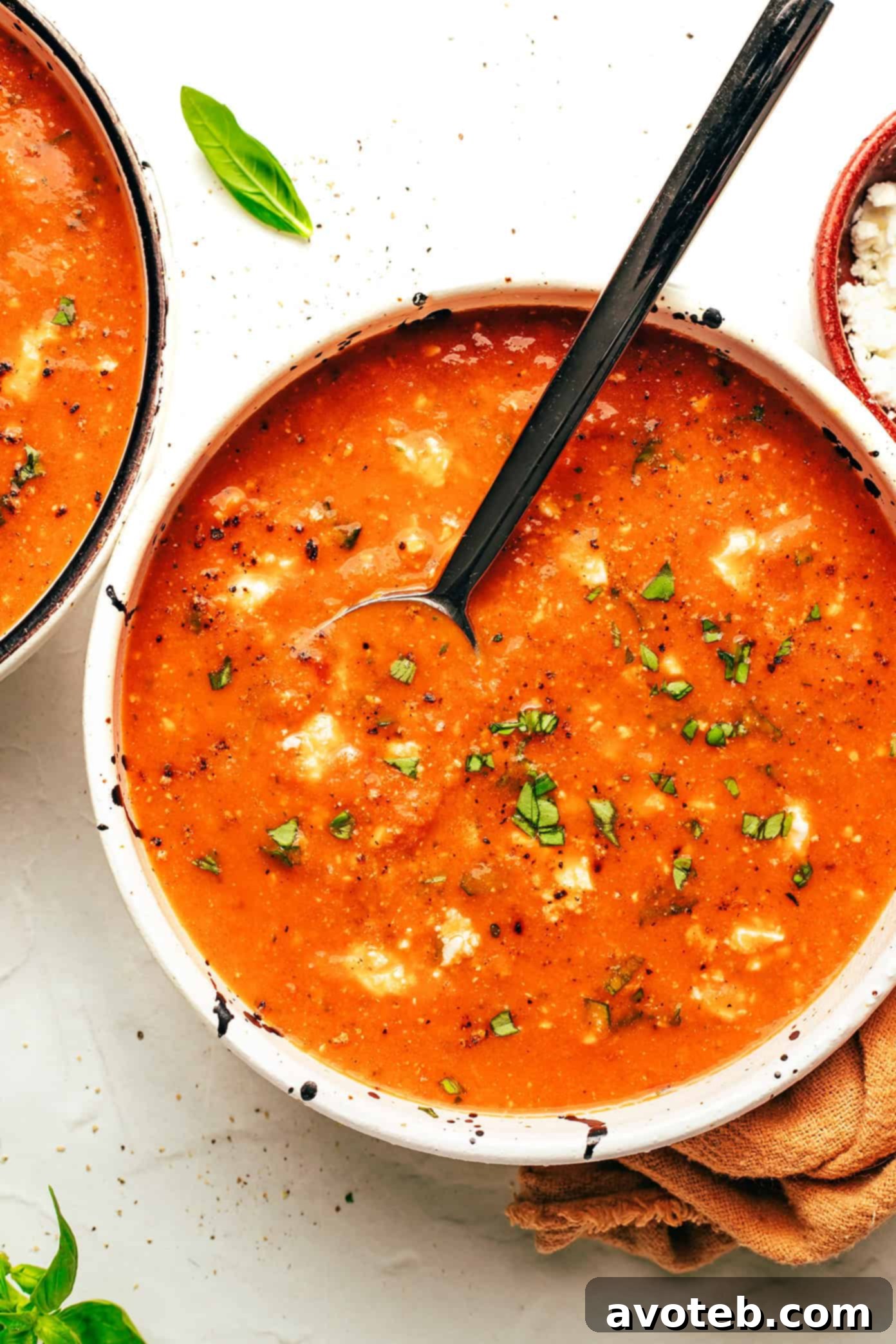 A vibrant display of fresh tomatoes, basil, and feta cheese, highlighting the quality ingredients used in the soup.
