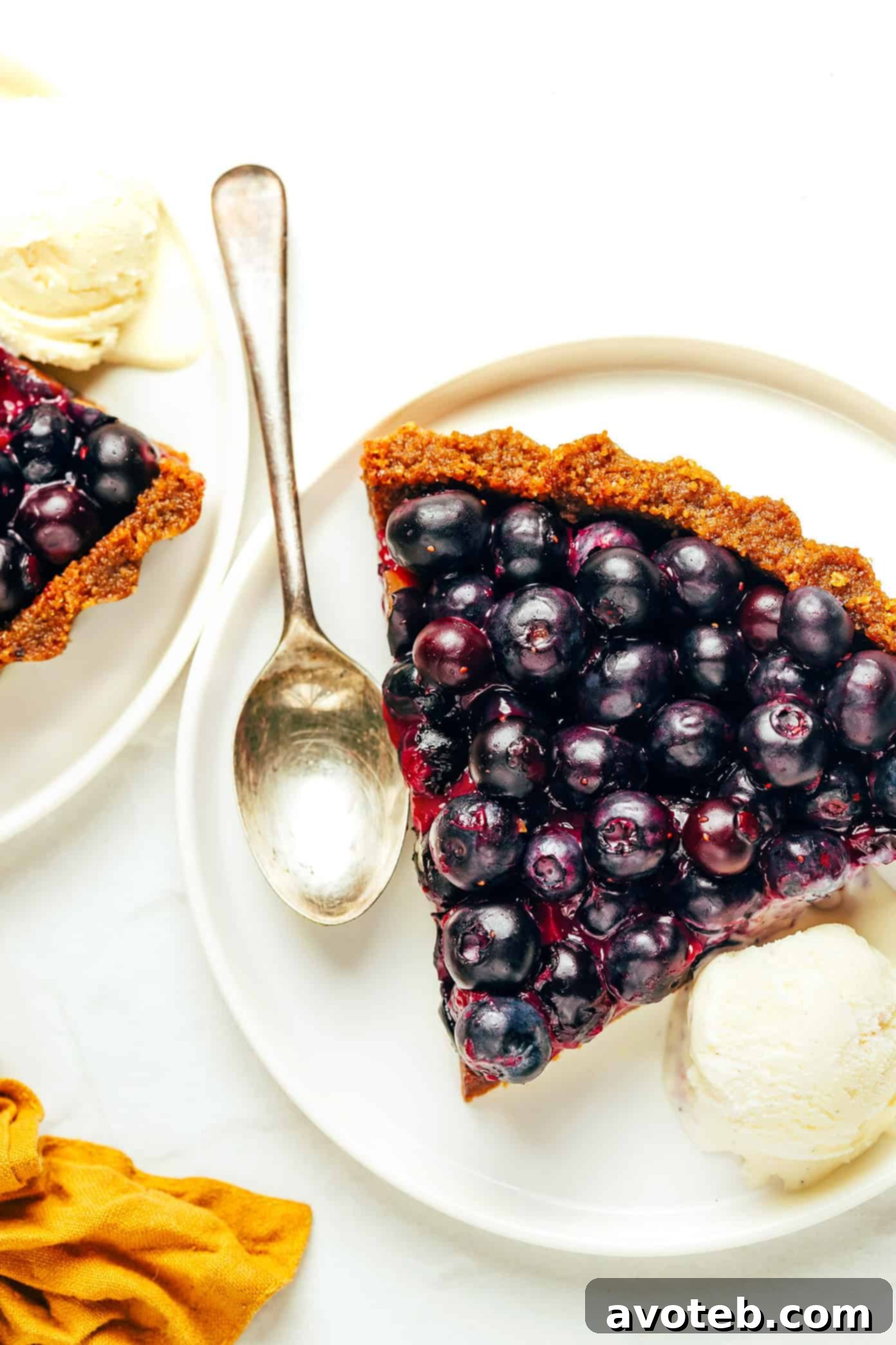 A close-up of a single serving of the blueberry tart, garnished with fresh mint leaves and a scoop of vanilla ice cream, creating a perfect dessert experience.