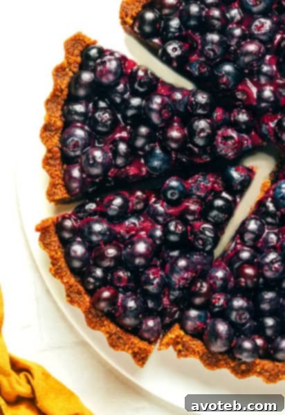 Freshly prepared no-bake blueberry tart with a golden gingersnap crust, topped with whole plump blueberries, ready to be chilled.