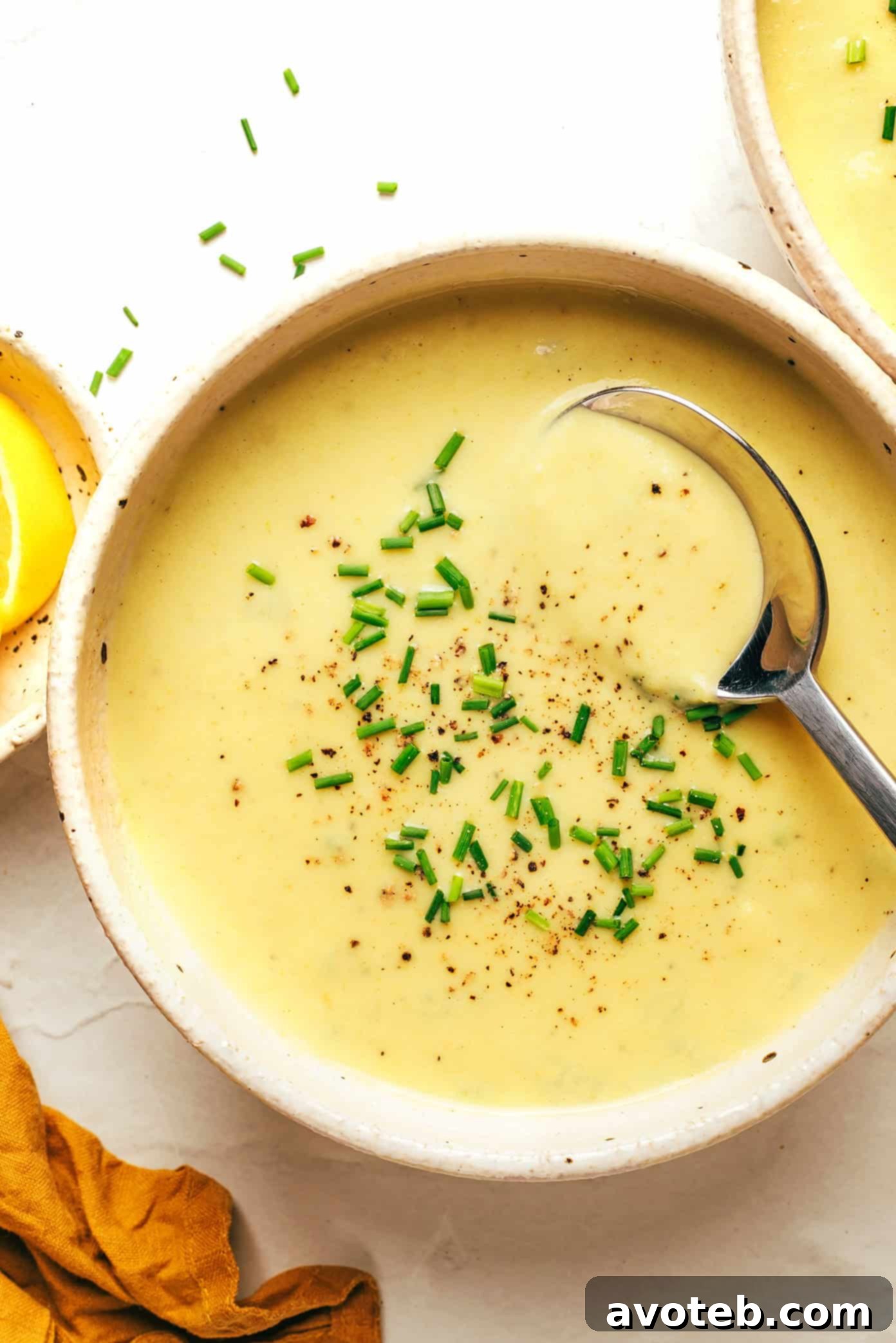 A vibrant bowl of creamy celery soup garnished with fresh chives, served with crusty bread for dipping.