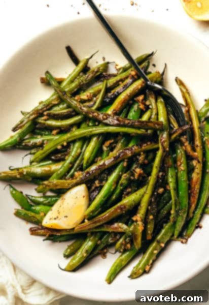 A large serving platter of blistered garlic green beans with lemon