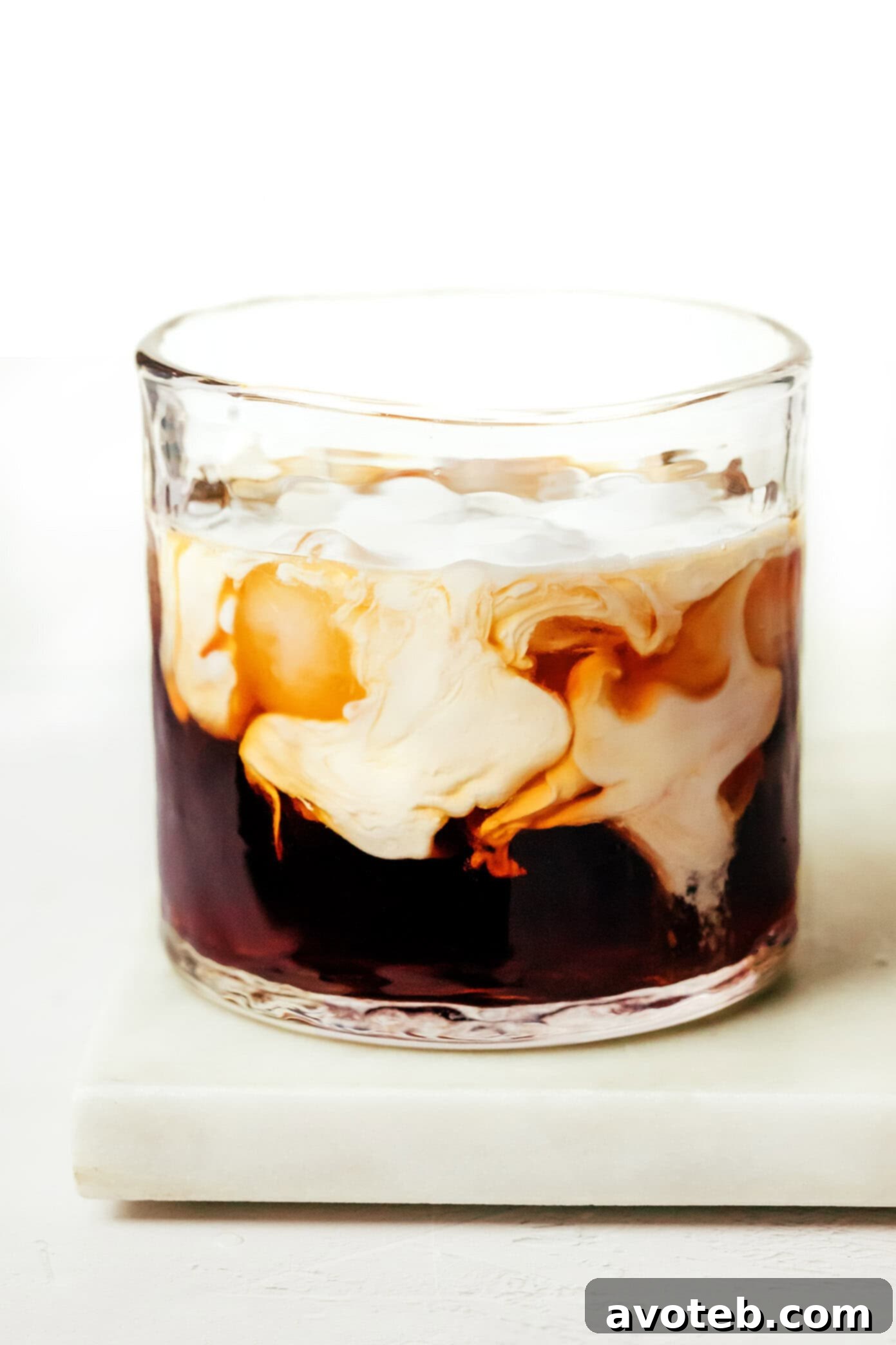 A close-up view of a White Russian cocktail in a glass, highlighting its rich, creamy texture and distinct layers
