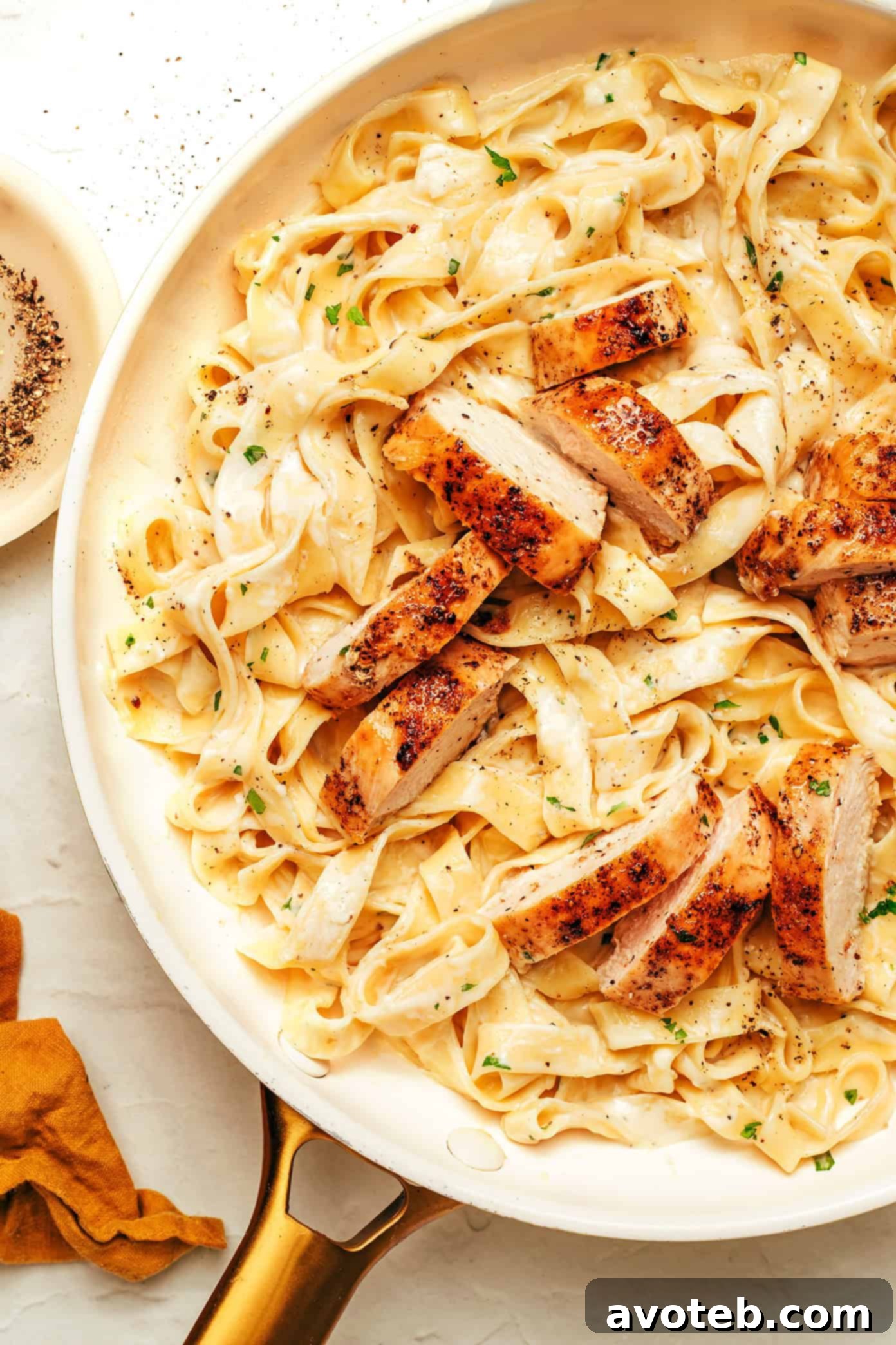 A serving of chicken fettuccine alfredo garnished with fresh herbs, ready to be eaten.