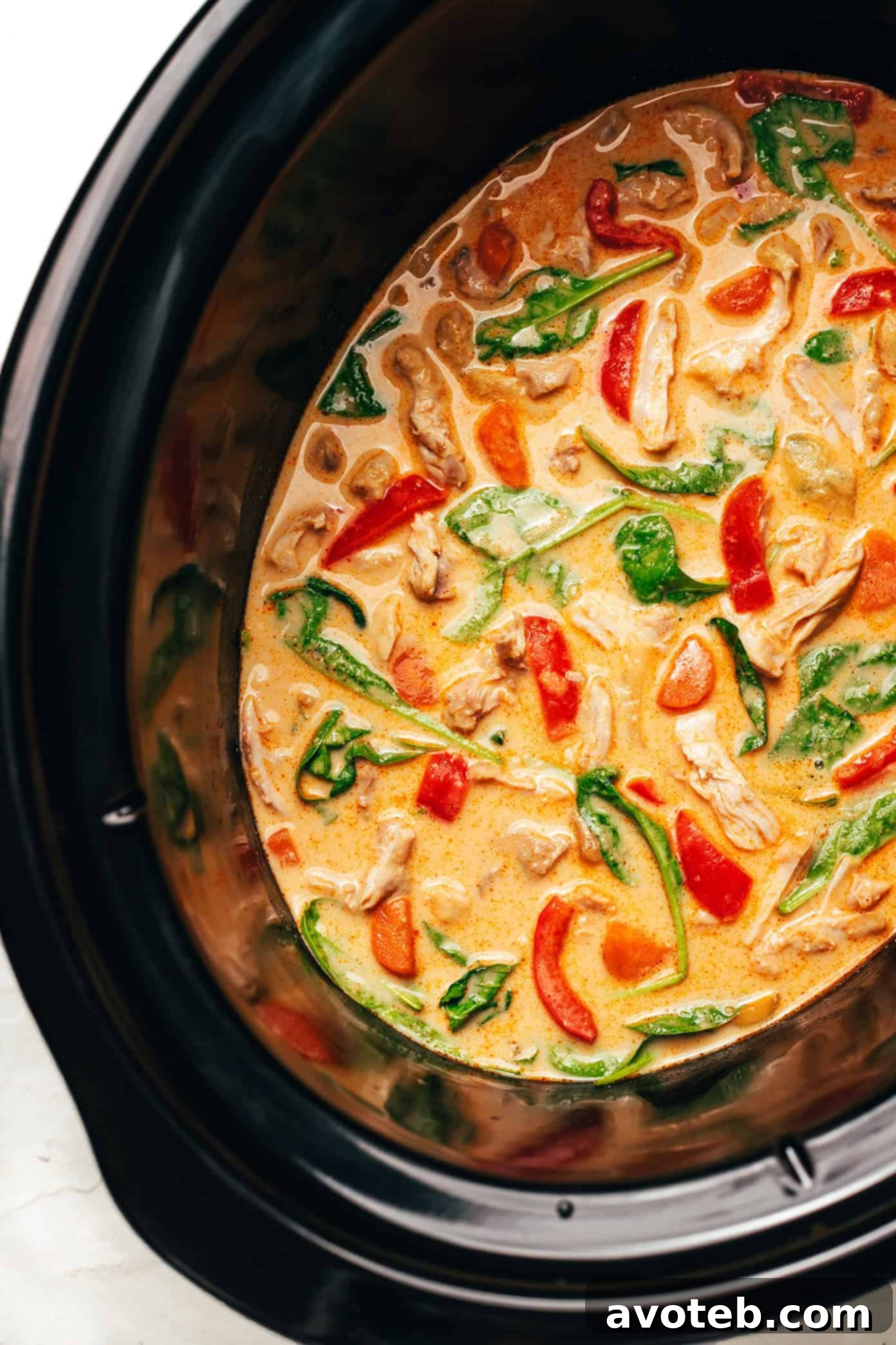 Slow cooker with cooked chicken satay before shredding
