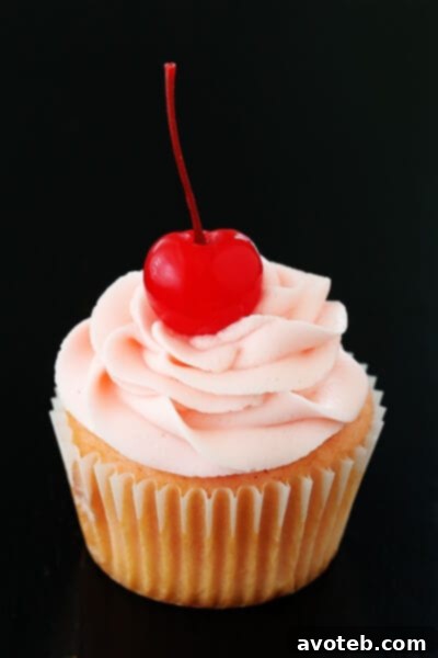 Close-up of a beautifully frosted Cherry Vanilla Cupcake garnished with a whole maraschino cherry