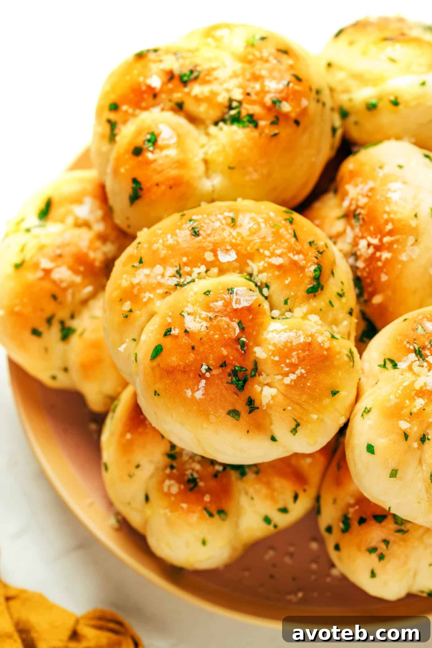 A basket full of freshly baked garlic knots, ready to be served, with a hint of Parmesan.