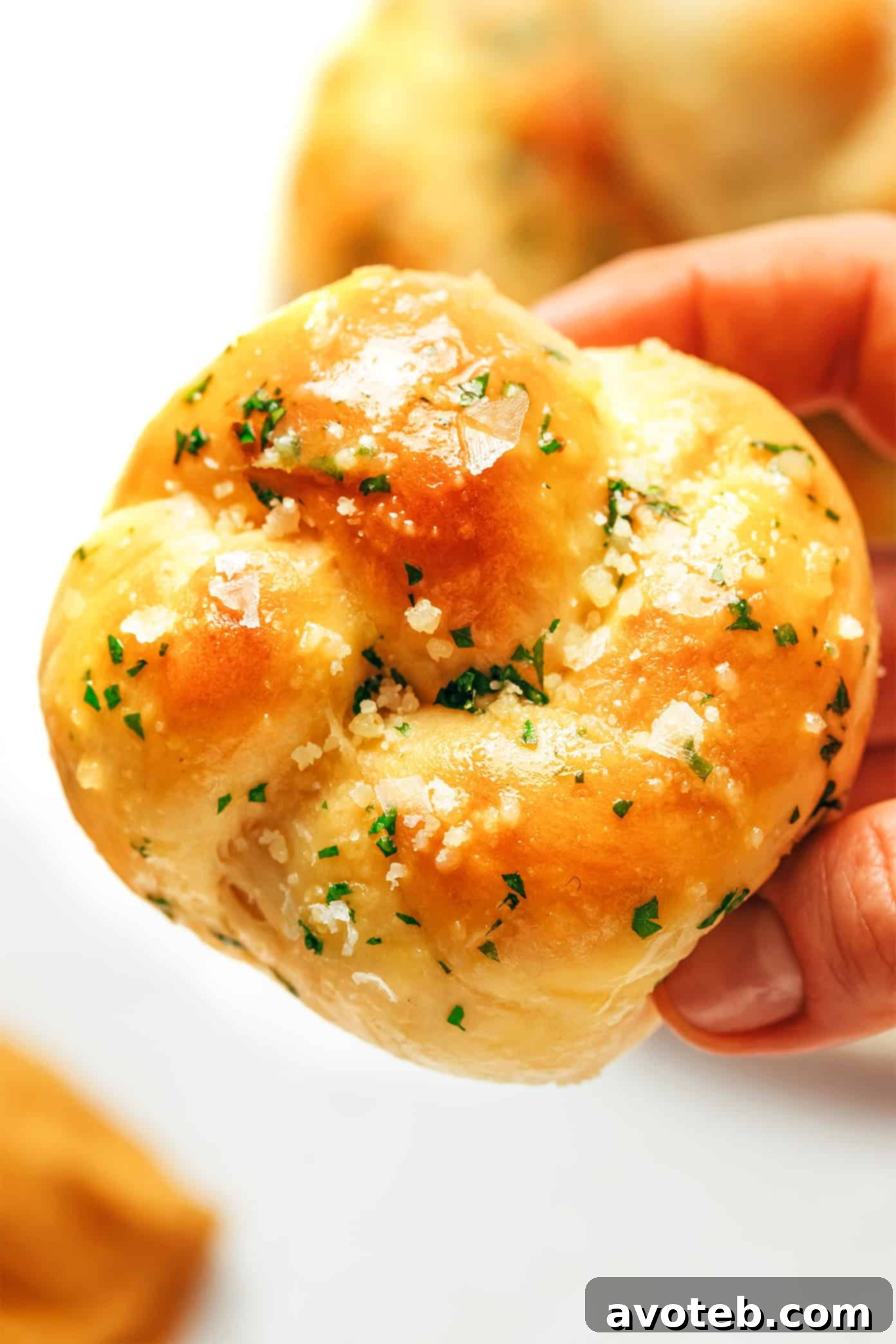 Overhead shot of a platter of warm, golden-brown garlic knots with melted garlic butter and herbs.