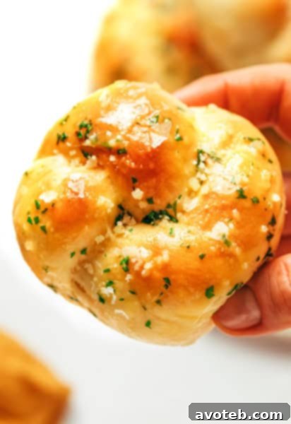 A basket full of warm, golden-brown garlic knots, dusted with Parmesan and fresh herbs.