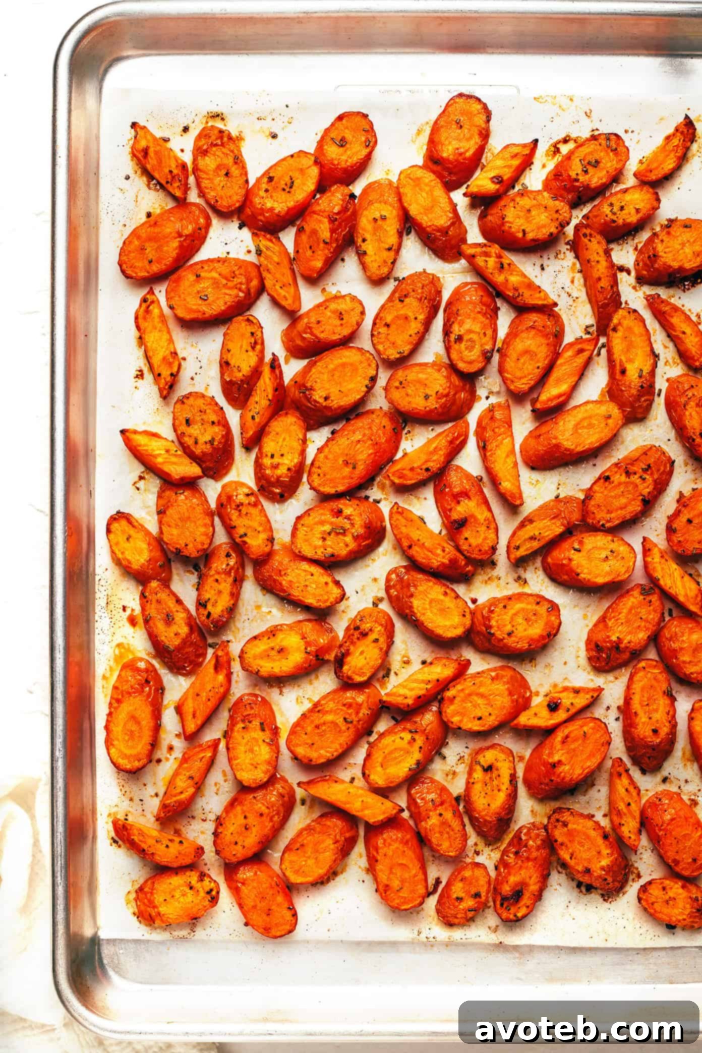 Finished roasted carrots in a serving bowl, garnished with fresh rosemary.