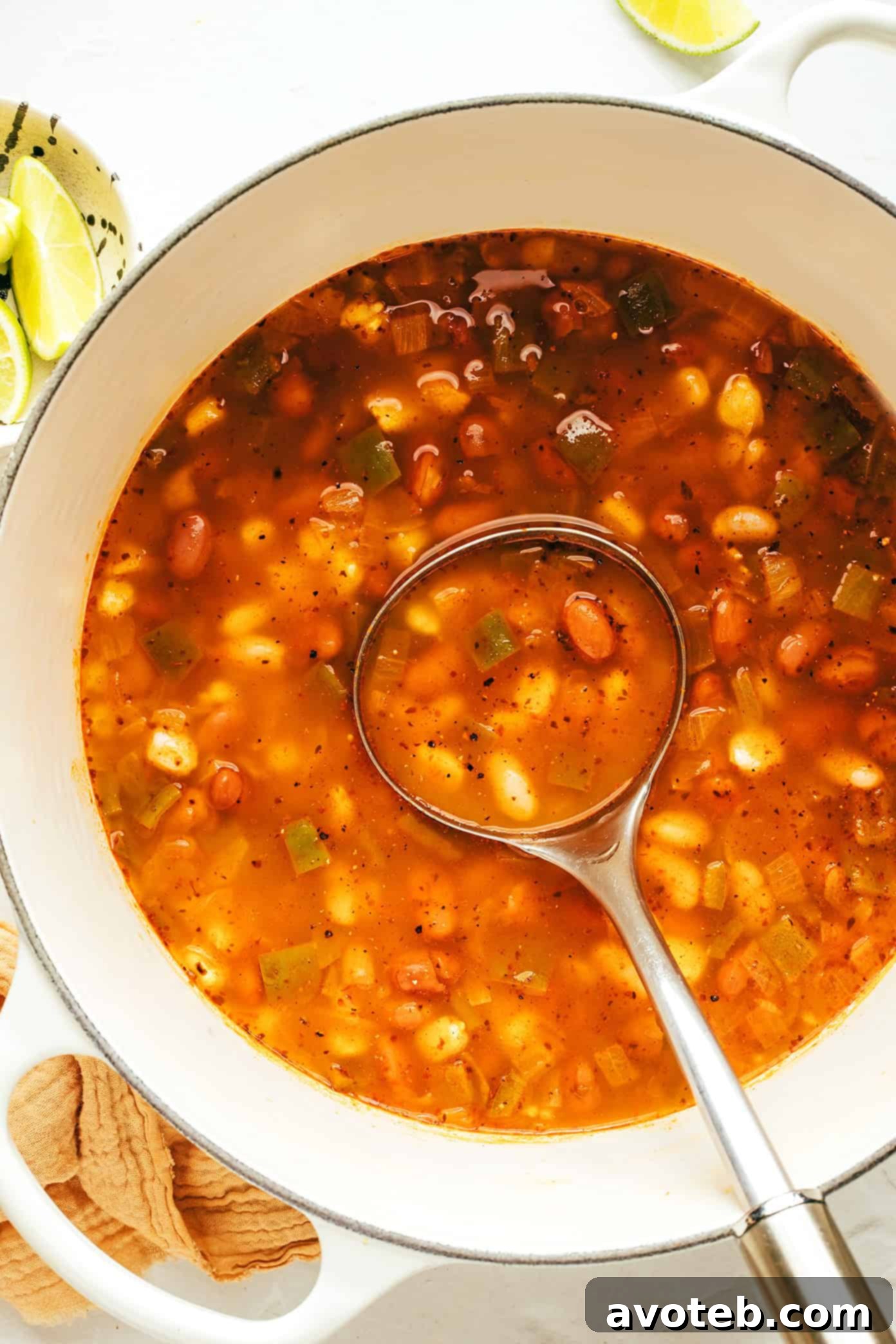 A wide shot of a pot of vegetarian pozole with various toppings laid out around it, ready to be served.