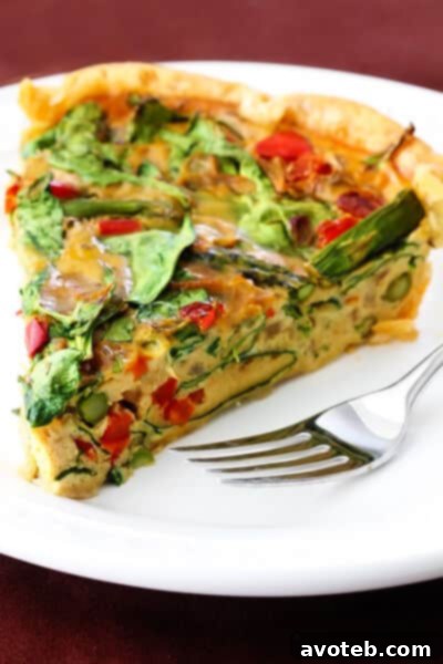A perfectly baked slice of dairy-free vegetable quiche, showcasing its fluffy texture and colorful vegetable filling.
