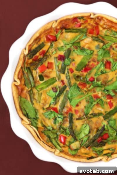 Tall, elegant slice of dairy-free vegetable quiche, showcasing layers of vegetables and a golden-brown crust.