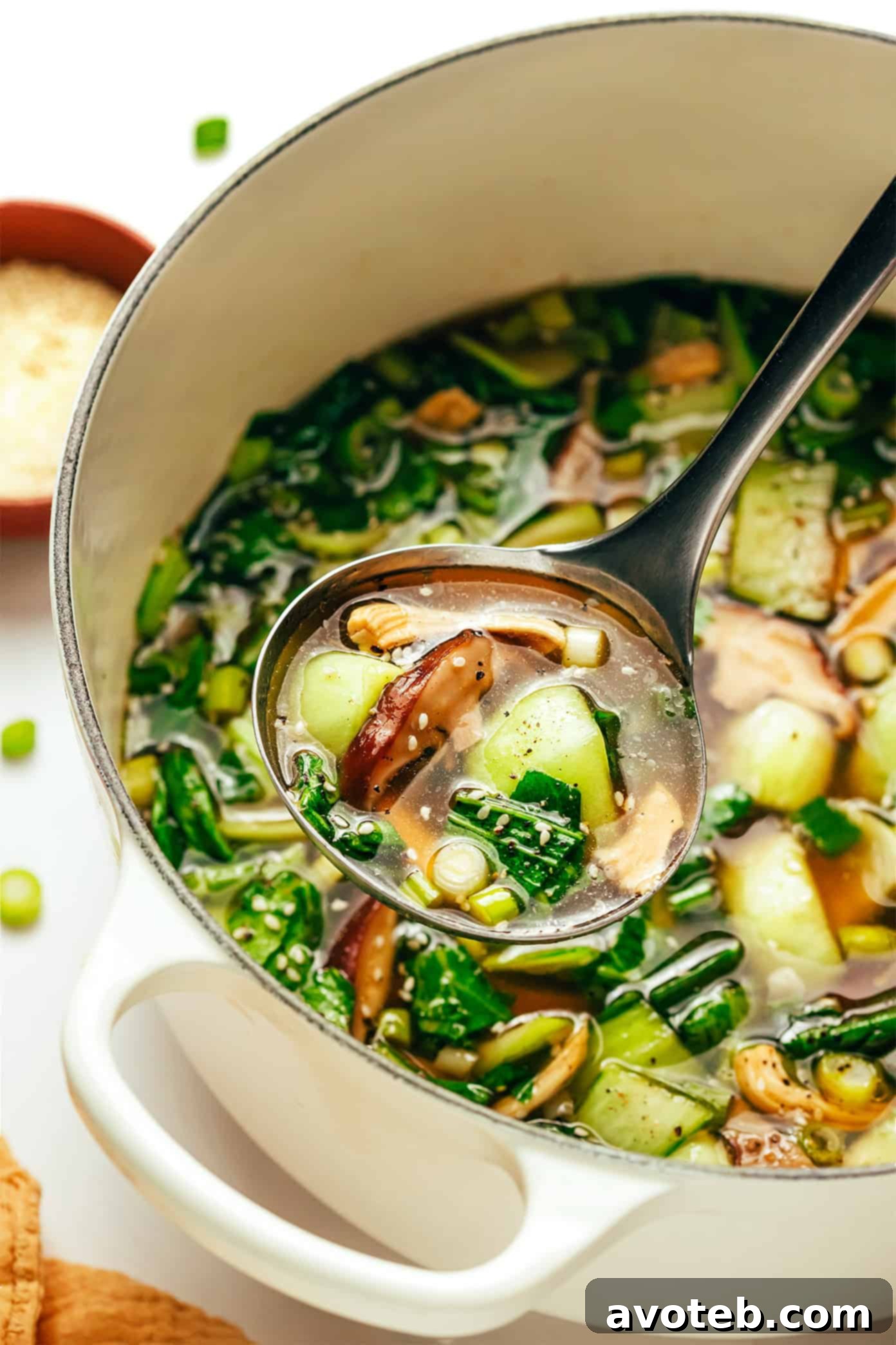 A bowl of ginger scallion chicken soup with a spoon, ready to be enjoyed, showcasing a vibrant and healthy meal.