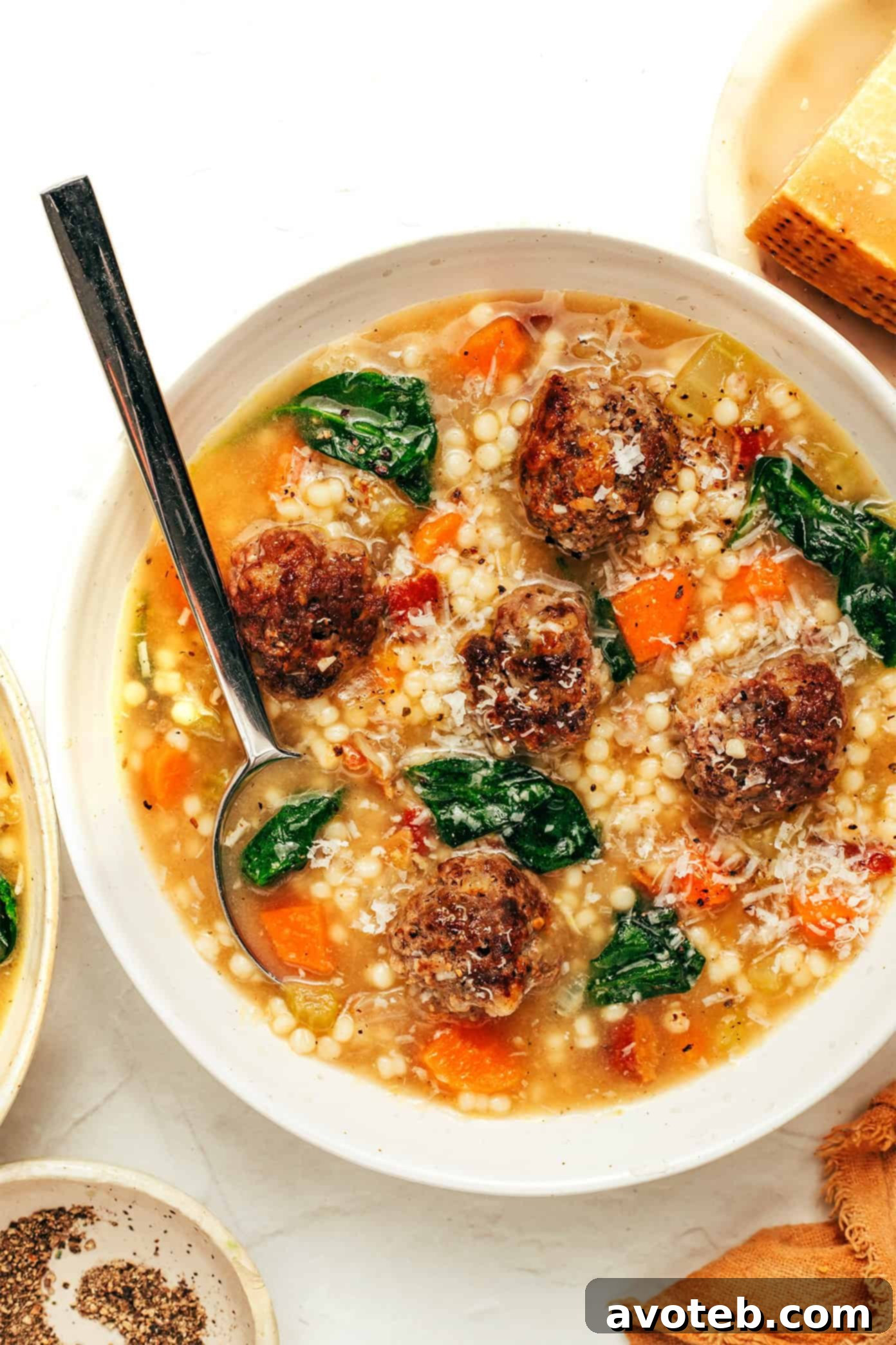Authentic Italian Wedding Soup 6 A close-up of a bowl of Italian Wedding Soup, showing the texture of the broth, meatballs, and spinach, with Parmesan cheese melting on top.