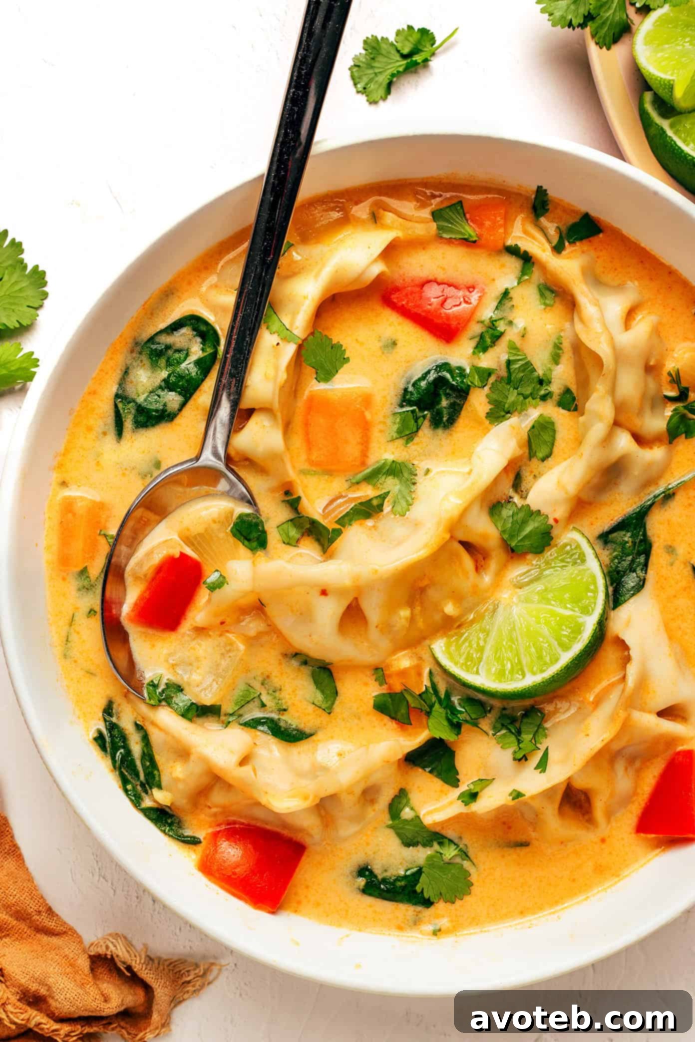 An overhead shot of a batch of Thai Red Curry Potsticker Soup in a large pot, with ingredients ready for serving.