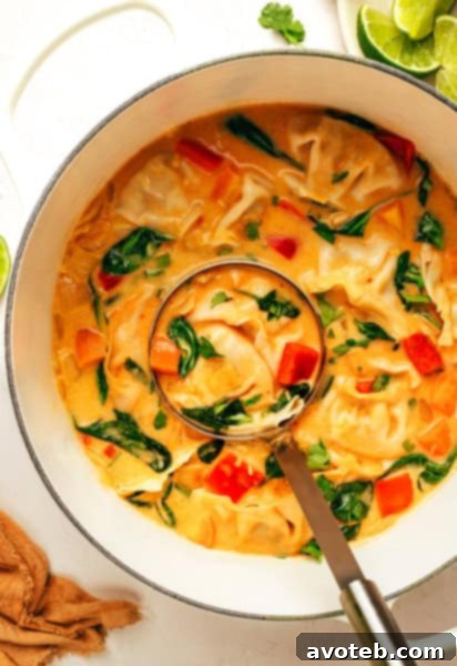 A vibrant bowl of Thai Red Curry Potsticker Soup, garnished with fresh cilantro and lime, ready to be enjoyed.