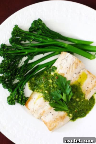 A close-up of a pan-seared Mahi Mahi fillet with a generous dollop of green chimichurri sauce, highlighting its vibrant colors.