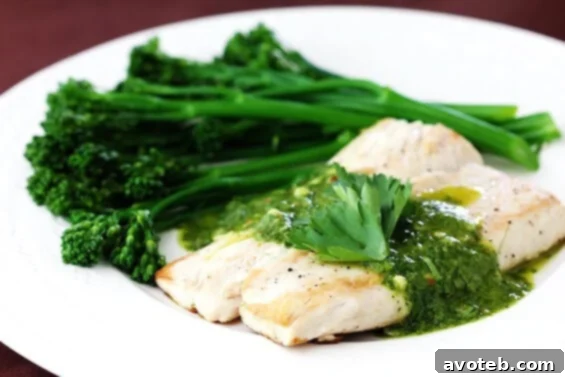 A dish of pan-seared Mahi Mahi with chimichurri sauce and blanched broccolini, ready to be served.