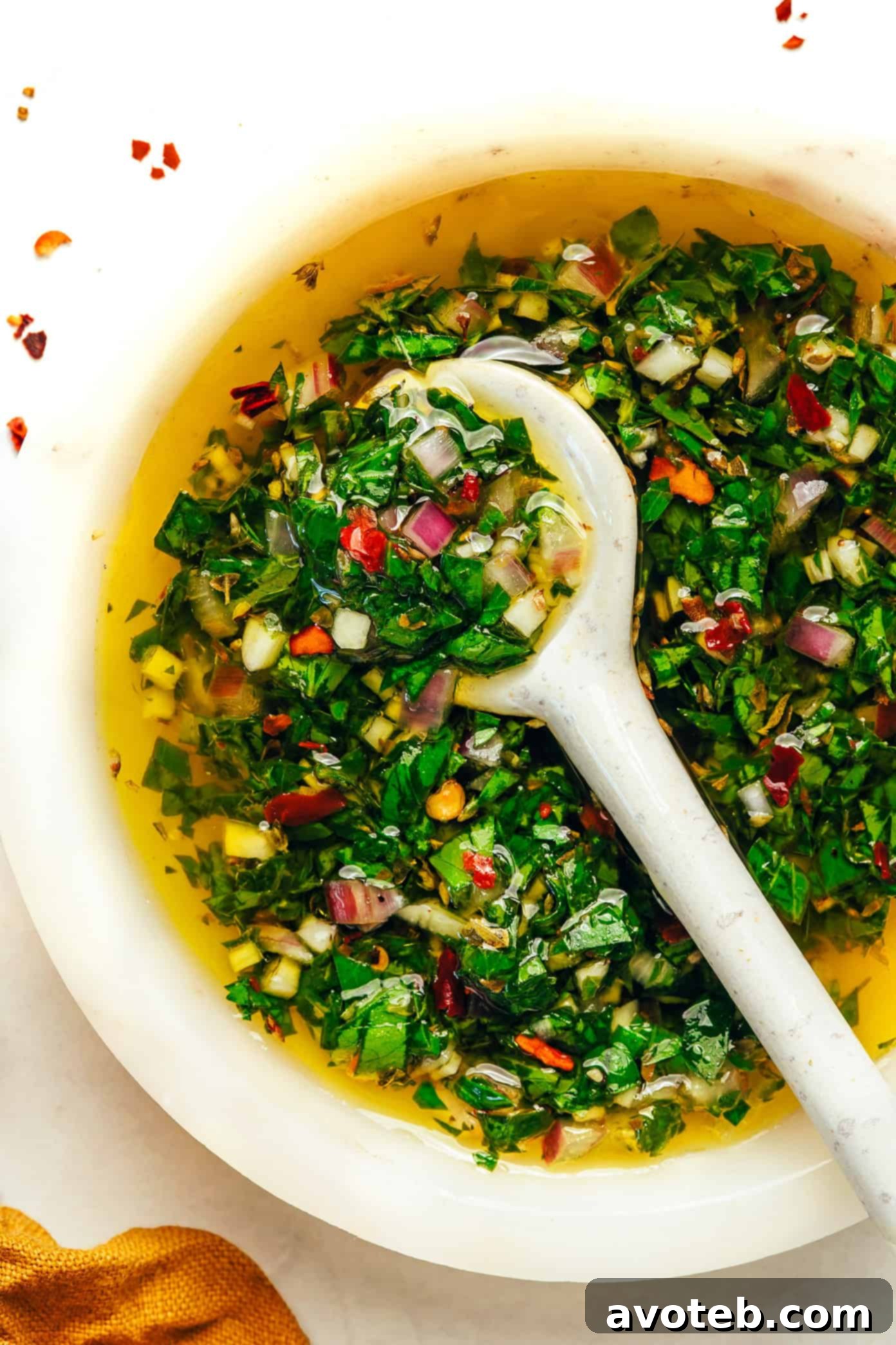 A bowl of chimichurri sauce, ready to be served with a rustic wooden spoon.