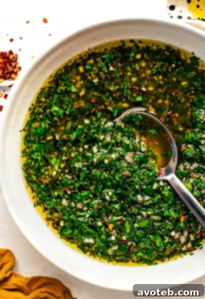 A close-up shot of a bowl of green chimichurri sauce, highlighting its vibrant texture.