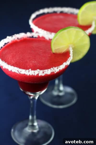 Close-up of a glass of Blackberry Lime Margarita garnished with lime and a blackberry.