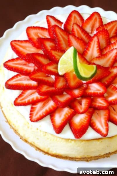 Strawberry Margarita Cheesecake | gimmesomeoven.com Close-up of Strawberry Margarita Cheesecake slice garnished with strawberries and lime