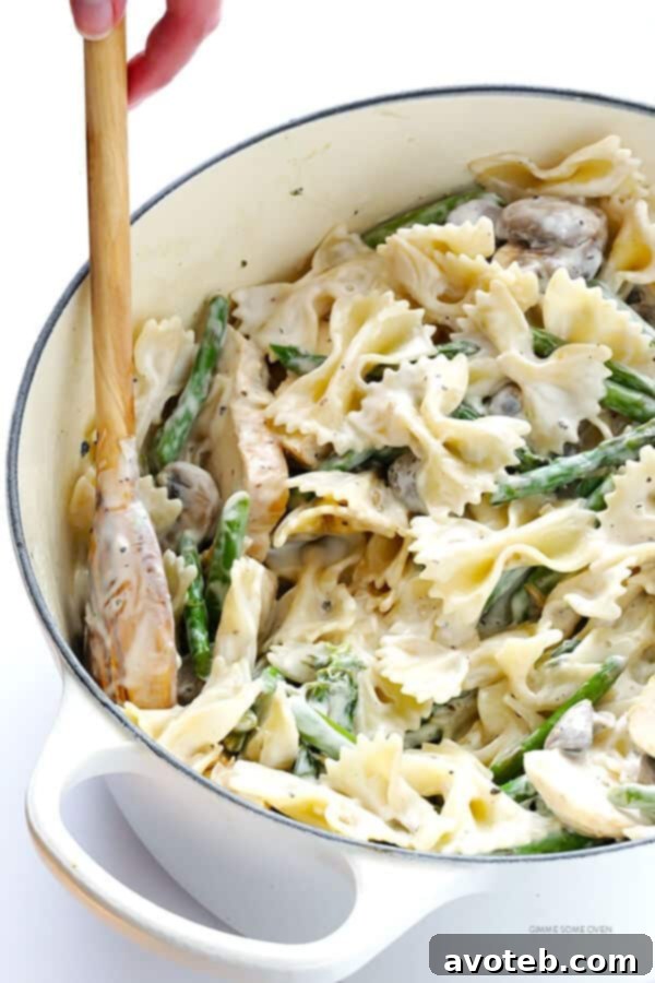 Chevre Chicken Pasta with Asparagus and Sautéed Mushrooms 3 A close-up shot of the finished pasta dish, showcasing the rich, creamy goat cheese sauce coating every strand of pasta, along with visible pieces of chicken, asparagus, and mushrooms.